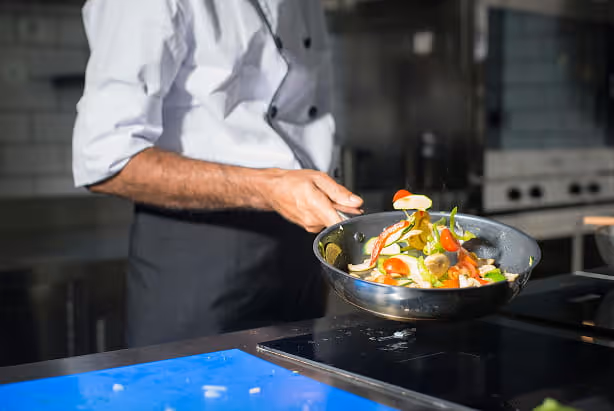 Chef en train de cuire des légumes dans une poêle